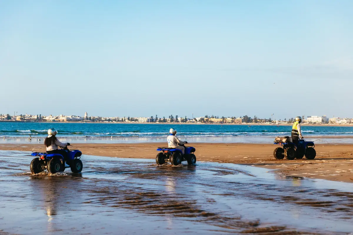 Quad bikes riding the wet sand at low tide near Essaouira
